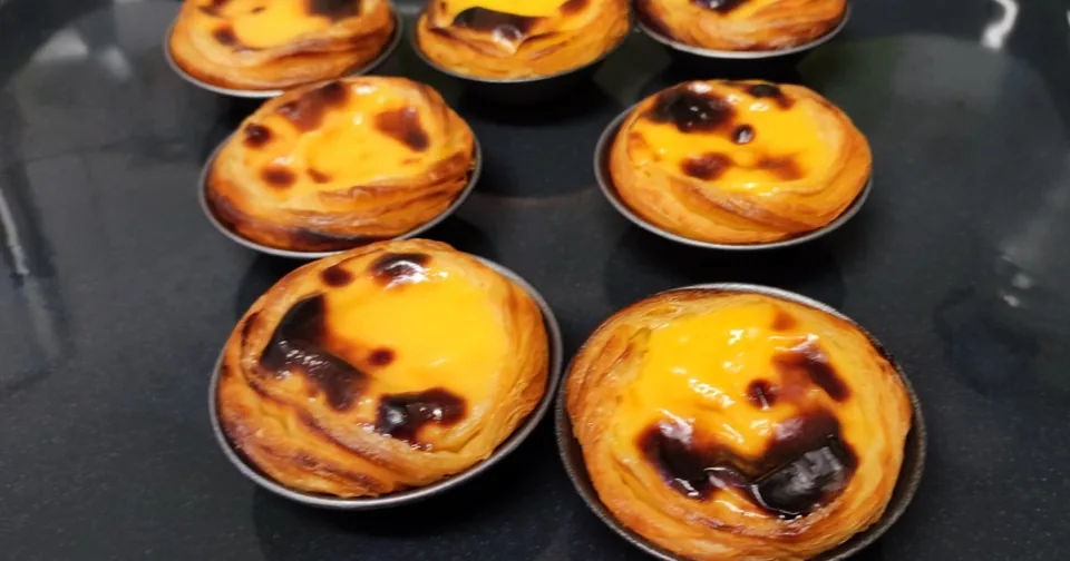 A tray of custard tarts with dark caramelised spots