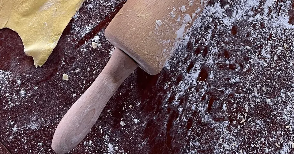 A wooden rolling pin on floured dough